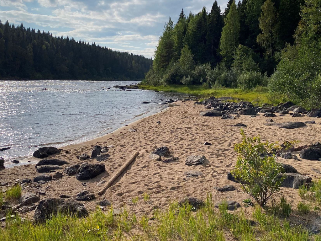liten vik vid en älv med en naturlig sandstrand