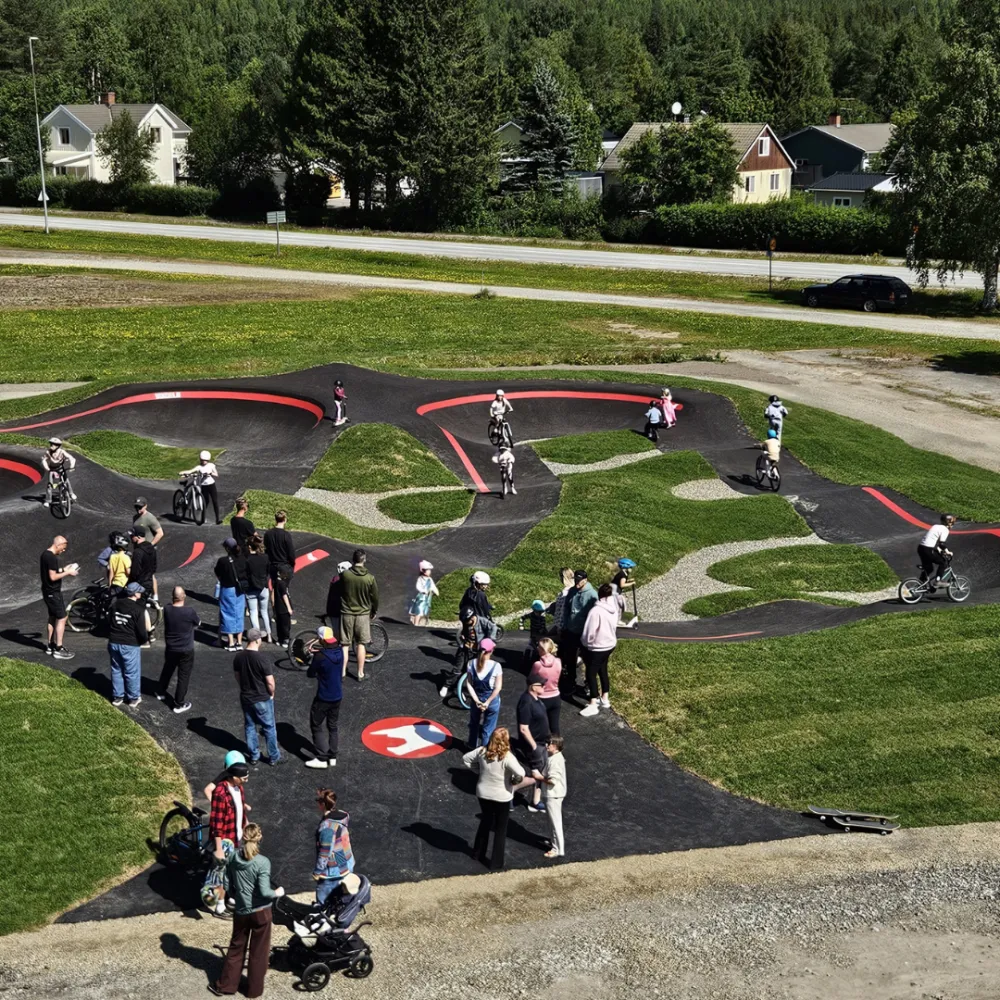 Barn cyklar på pumptrackens asfalterade slingor.