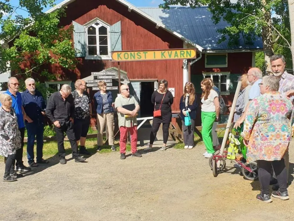 personer utanför en röd kvarnbyggnad med skylten konst i kvarn
