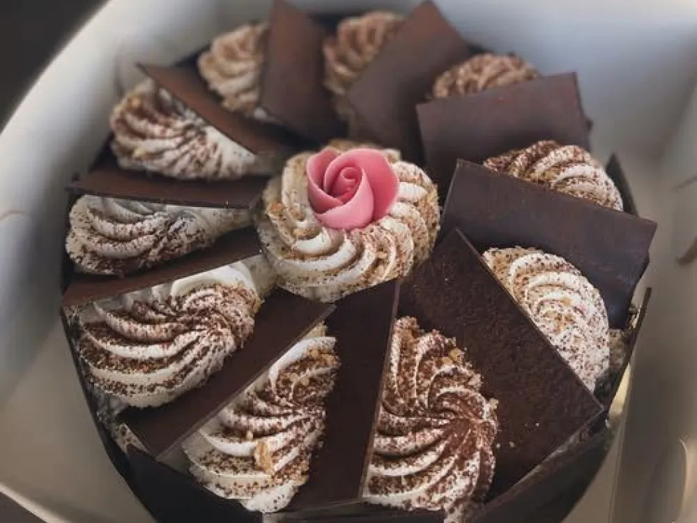 chokladtårta dekorerad med grädde och en marsipanros