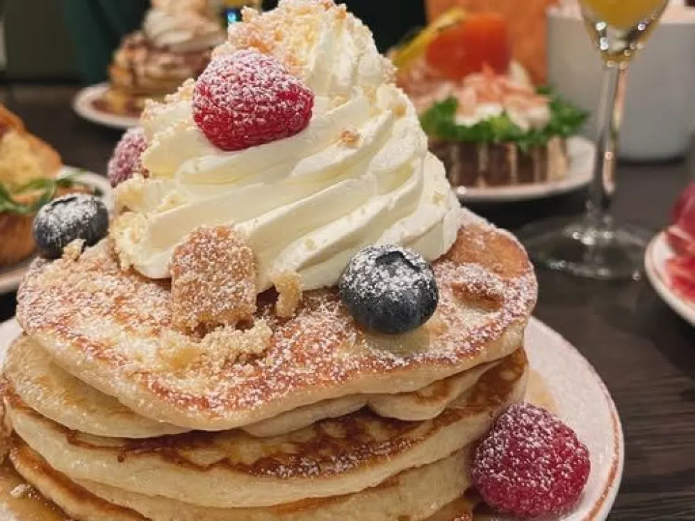amerikanska pannkakor travade på en tallrik med grädde och bär