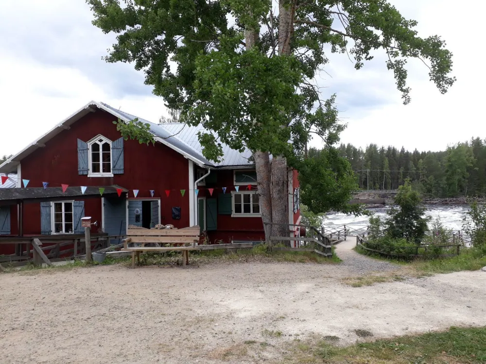gammalt rött kvarnhus invid en forsande älv