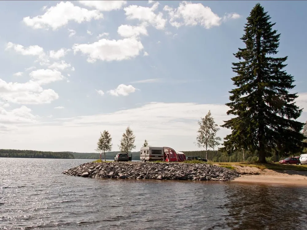 udde i en norrländsk sjö där det står en husvagn och campar